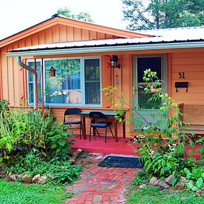 A small cheerful brightly painted house surrounded by plants