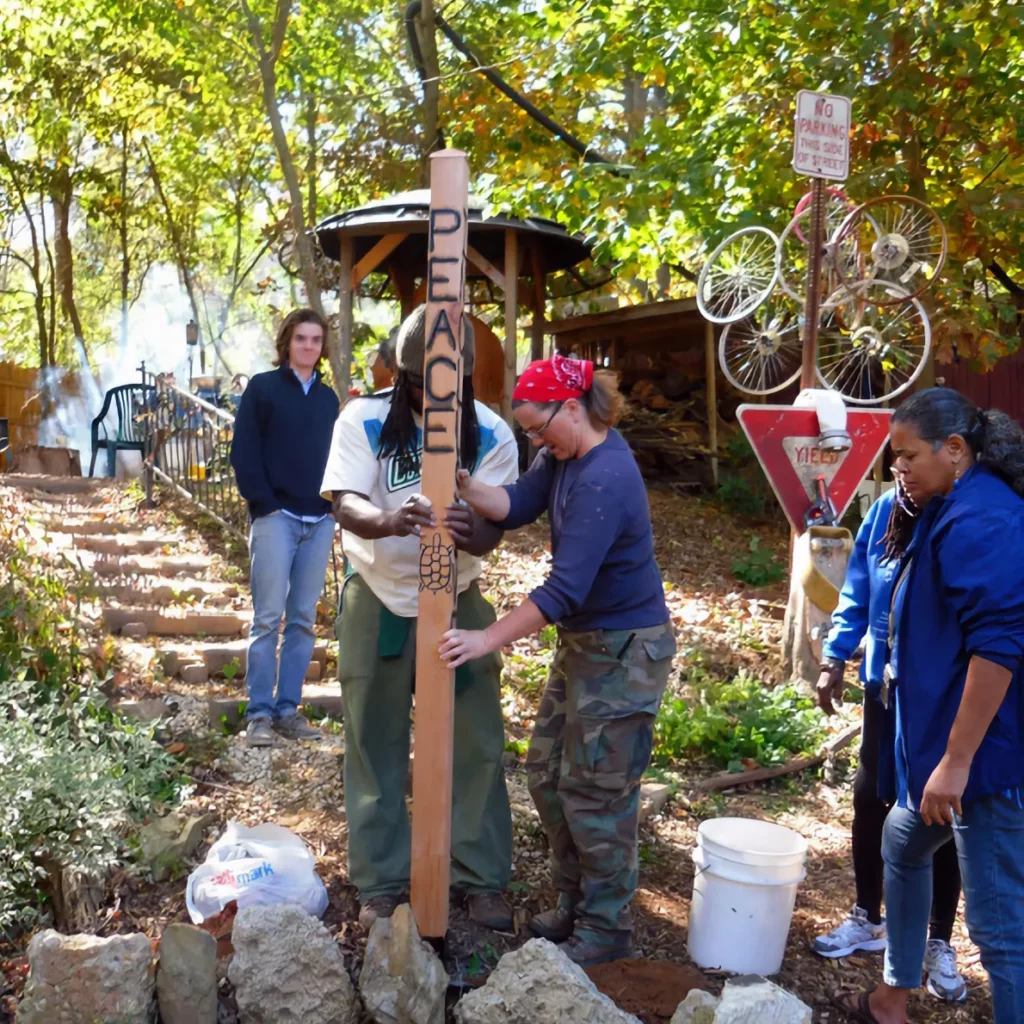 A diverse group of volunteers erects a Peace Garden sign together